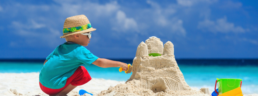 A small child building a sand castle on a tropical beach