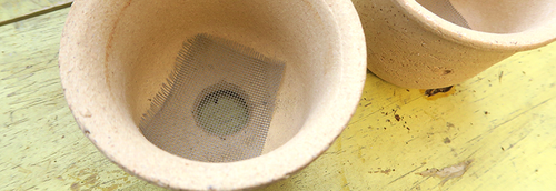 A planter with a drainage hole and bottom mesh covering.