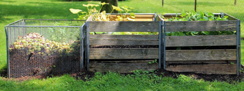 A home gardener's composting station showing three separate bins representing the various stages of decomposition